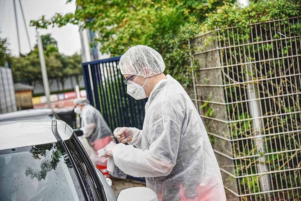 Personen im Auto werden von DRK sanitätern durch das Fenster auf Corona getestet
