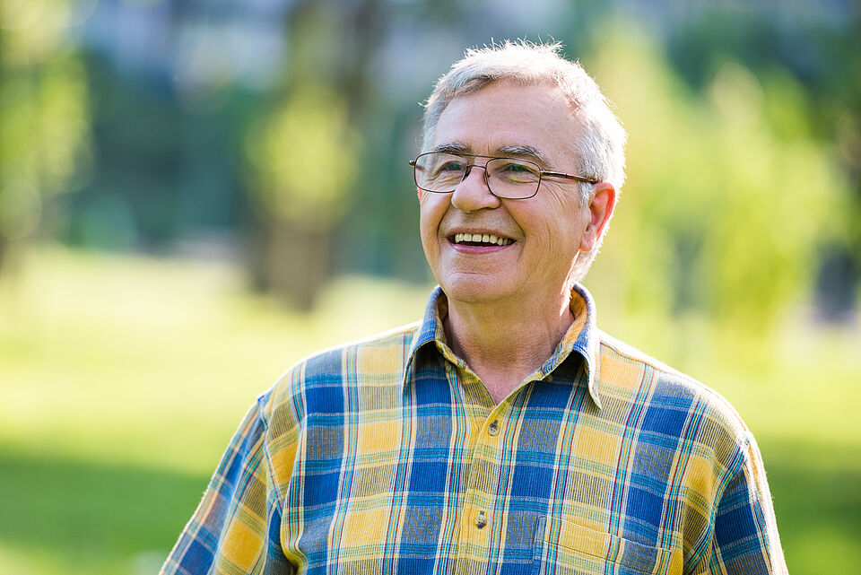 fröhlicher Mann mit kariertem Hemd auf Blumenwiese