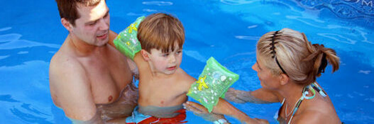 Eltern schwimmen mit ihrem Kind Kind mit Eltern im Wasser im Schwimmbad