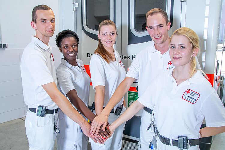 fünf Rettungssanitäter geben sich die Hände