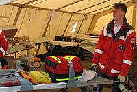zwei Rettungssanitäter im Rettungszelt mit vorbereiteter Lieg