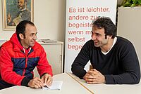 zwei Personen sitzen zusammen am Tisch und unterhalten sich 