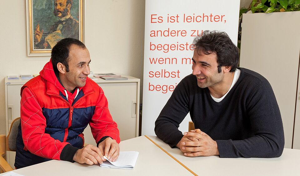 zwei Personen sitzen zusammen am Tisch und unterhalten sich 