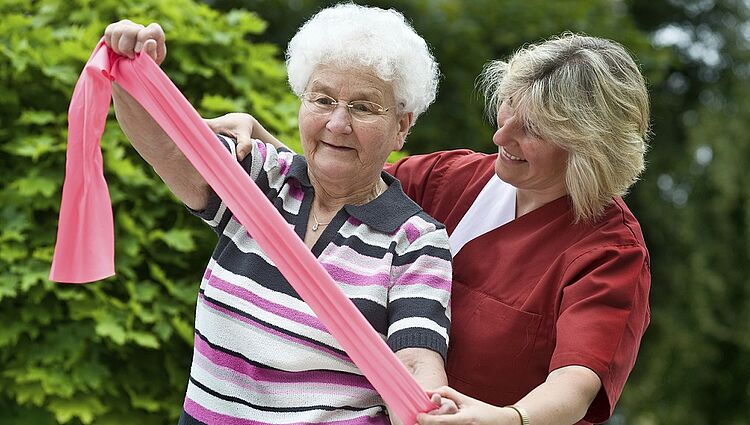 Gymnastik für Senioren Eine Seniorin wird bei der Gymnastik unterstützt