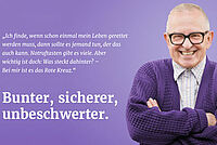Älterer Herr in einer lila STrickjacke lacht in die KAmera