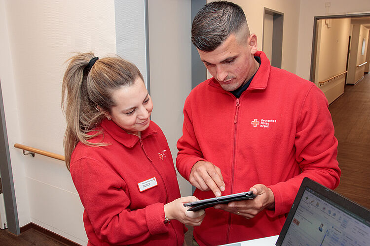 Zwei Mitarbeitende besprechen die Daten auf einem Tablet.