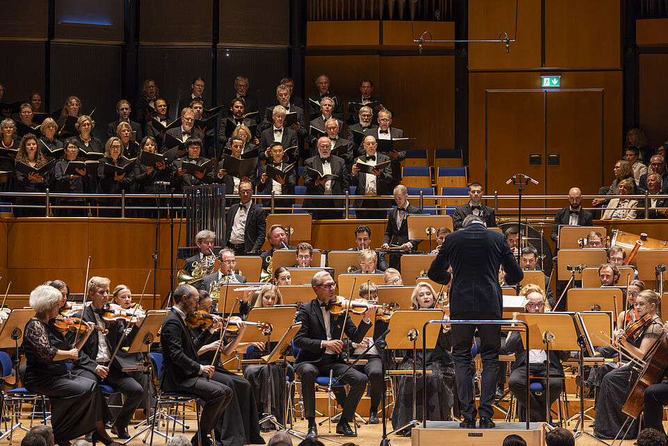 Foto: Ansgar van Treeck Blick aufs Orchester auf der Bühne und darüber im Rang ein Chor